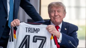 German Chancellor, Friedrich Merz, gives Trump a German national team t-shirt with his last name and the number 47 on...